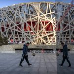 
              FILE - A man and a boy walk past the National Stadium, also known as the Bird's Nest, which will again be a venue for the 2022 Beijing Winter Olympics, in Beijing on Feb. 2, 2021. Ai is one of China's most famous artists, and many regard him as one of the world's greatest living artists. Working with the Swiss architectural firm Herzog & de Meuron, he helped design the Bird's Nest stadium, the centerpiece of Beijing's 2008 Summer Olympics. The stadium will also host the opening ceremony for Beijing's Winter Olympics on Feb. 4, 2022. (AP Photo/Mark Schiefelbein, File)
            