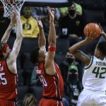 
              Oregon guard Jacob Young (42) shoots as Utah's Brendan Carlson, left, and Marco Anthony defend during the second half of an NCAA college basketball game in Eugene, Ore., Saturday, Jan. 1, 2022. (AP Photo/Thomas Boyd)
            