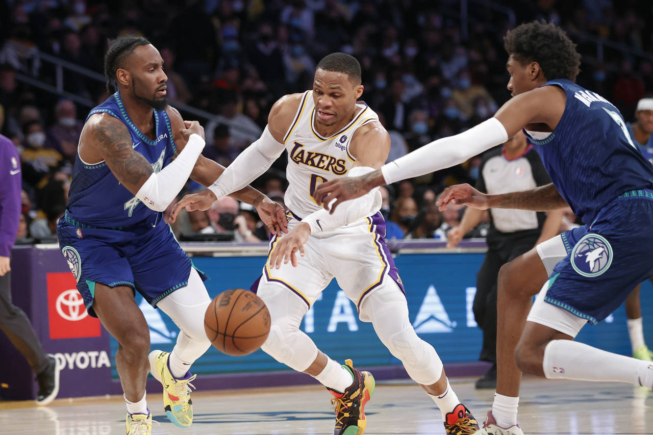 Los Angeles Lakers guard Russell Westbrook, center, drives between Minnesota Timberwolves guard Jay...