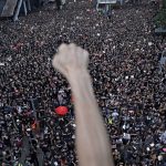 
              FILE - A protester raises a fist near protesters marching on the streets against an extradition bill in Hong Kong on June 16, 2019. From the military suppression of Beijing’s 1989 pro-democracy protests to the less deadly crushing of Hong Kong’s opposition four decades later, China’s long-ruling Communist Party has demonstrated a determination and ability to stay in power that is seemingly impervious to Western criticism and sanctions. (AP Photo/Vincent Yu, File)
            