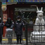 
              Security personnel wearing face masks to help protect from the coronavirus stand on duty next to a statue on a shopping street in Beijing, Sunday, Jan. 23, 2022. Chinese authorities have called on the public to stay where they are during the Lunar New Year instead of traveling to their hometowns for the year's most important family holiday. (AP Photo/Andy Wong)
            