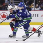 
              Florida Panthers' Anton Lundell (15) checks Vancouver Canucks' Elias Pettersson (40) during the third period of an NHL hockey game Friday, Jan. 21, 2022, in Vancouver, British Columbia. (Darryl Dyck/The Canadian Press via AP)
            