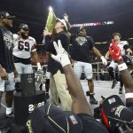 
              Georgia head coach Kirby Smart kisses the trophy while Zamir White (from left) Jamaree Salyer, Nakobe Dean and quarterback Stetson Bennett celebrate on stage winning the College Football Playoff Championship game over Alabama, early Tuesday, Jan. 11, 2022, in Indianapolis. (Curtis Compton/Atlanta Journal-Constitution via AP)
            