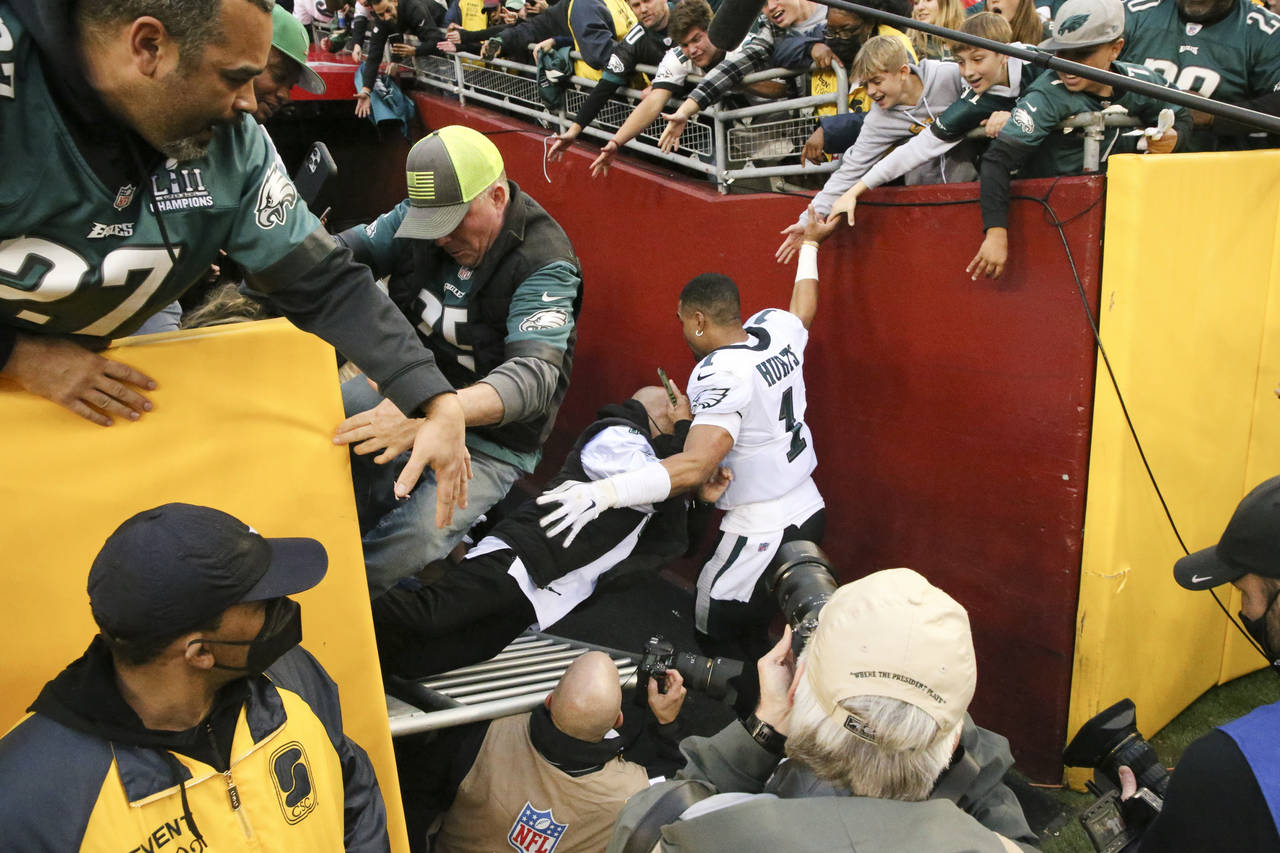 Fans fall on Philadelphia Eagles quarterback Jalen Hurts (1) after beating the Washington Football ...