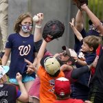 
              FILE - Fans wearing protective face masks go for a ball thrown from the outfield during a spring training baseball game between the Washington Nationals and New York Mets, Sunday, March 21, 2021, in West Palm Beach, Fla. Spring training games might not count in the official standings, but they certainly count for the pocketbooks of business owners in Arizona and Florida. They're also a much-anticipated destination for fans who come for the warm sunshine and the laid-back atmosphere.(AP Photo/Lynne Sladky, File)
            