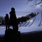 
              Julia Lindquist, 4, left, and Miles Stanton, 7, stand in silhouette on tree stumps and look over the five ski jump runs at the Norge Ski Club Tuesday, Jan. 18, 2022, in Fox River Grove, Ill. Lindquist was drawn to the sport when her parents would drive around the area for something safe to do during the COVID-19 pandemic last year. Each time the family of four drove near the club last year, the little girl in the back of the car told her parents of her hopes and dreams. "She didn't stop saying she wanted to do it," said her father, Jake. "I want to jump. It still hasn't let up."(AP Photo/Charles Rex Arbogast)
            
