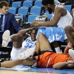 
              UCLA guard David Singleton, left, hits his head on a chair as he and Oregon State guard Tre' Williams slide into the UCLA bench while going after a loose ball during the first half of an NCAA college basketball game Saturday, Jan. 15, 2022, in Los Angeles. (AP Photo/Mark J. Terrill)
            