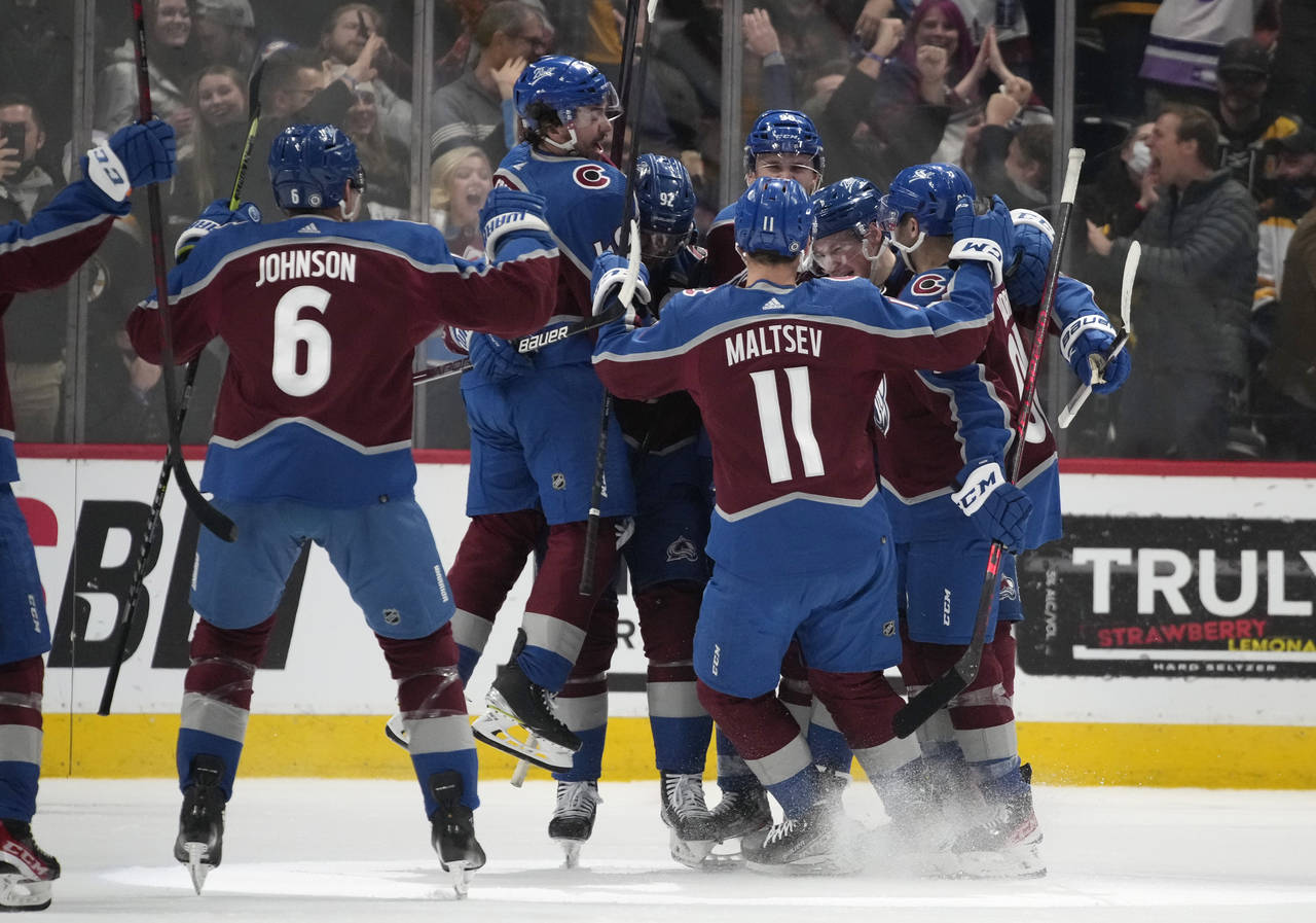 Colorado Avalanche players celebrate with defenseman Cale Makar after his power-play goal in overti...