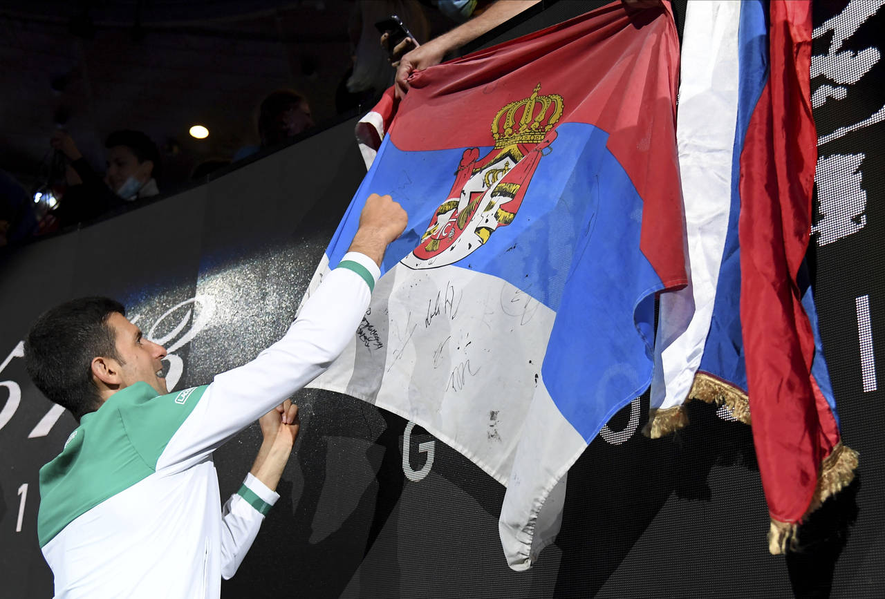 FILE - Serbia's Novak Djokovic signs autographs after defeating Russia's Daniil Medvedev during the...