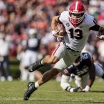 
              FILE - Georgia quarterback Stetson Bennett (13) carries the ball against Auburn during the first half of an NCAA college football game Saturday, Oct. 9, 2021, in Auburn, Ala. Georgia plays Alabama in the College Football Playoff national championship game on Jan. 10, 2022. (AP Photo/Butch Dill)
            