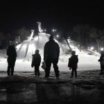 
              Kids and parents stand in silhouette and look out over the five ski jumps Tuesday, Jan. 18, 2022, at the Norge Ski Club in Fox River Grove, Ill. Three men will represent the club for a second straight Winter Olympics. (AP Photo/Charles Rex Arbogast)
            