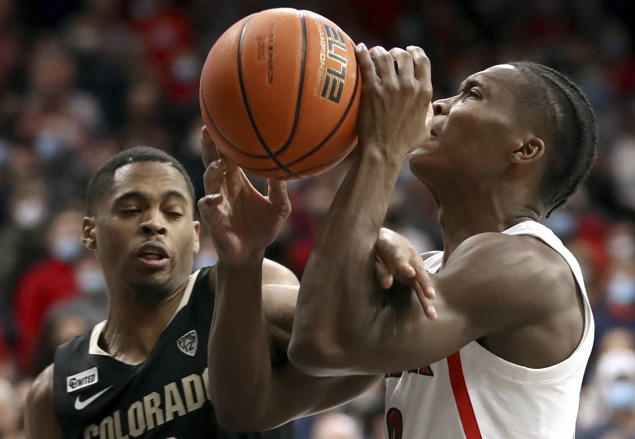 Arizona guard Bennedict Mathurin (0) gets hacked by Colorado guard Keeshawn Barthelemy (3) on his w...