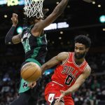 
              Chicago Bulls' Coby White (0) passes off under the net against Boston Celtics' Robert Williams III (44) during the first half of an NBA basketball game, Saturday, Jan. 15, 2022, in Boston. (AP Photo/Michael Dwyer)
            