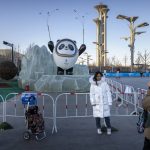 
              A woman wearing a face mask to protect against coronavirus watches as another woman poses for a photo with a statue of the Winter Olympic mascot Bing Dwen Dwen near the Olympic Green in Beijing, Wednesday, Jan. 12, 2022. The Chinese capital is on high alert ahead of the Winter Olympics as China continues to report new cases of COVID-19 in the nearby city of Tianjin. (AP Photo/Mark Schiefelbein)
            