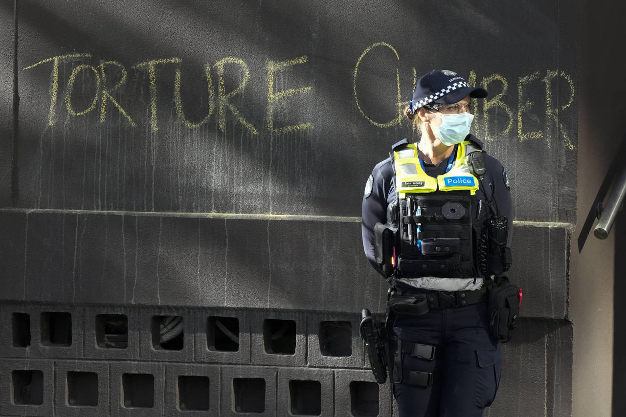A police officer stands by a slogan on the wall outside the Park Hotel, used as an immigration dete...