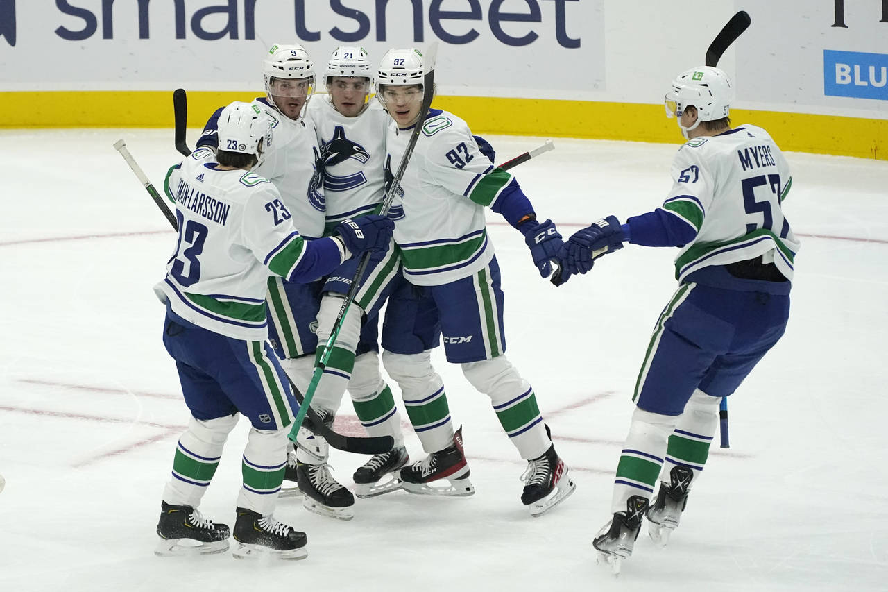 Vancouver Canucks right wing Vasily Podkolzin, second from right, is greeted by teammates after he ...