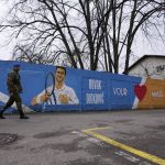 
              Serbian Army soldiers pass a mural depicting Serbian tennis player Novak Djokovic on a wall in Belgrade, Serbia, Thursday, Jan. 6, 2022. The Australian government has denied No. 1-ranked Novak Djokovic entry to defend his title in the year's first tennis major and canceled his visa because he failed to meet the requirements for an exemption to the country's COVID-19 vaccination rules. (AP Photo/Darko Vojinovic)
            