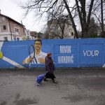 
              A woman passes a mural depicting Serbian tennis player Novak Djokovic on a wall in Belgrade, Serbia, Thursday, Jan. 6, 2022. The Australian government has denied No. 1-ranked Novak Djokovic entry to defend his title in the year's first tennis major and canceled his visa because he failed to meet the requirements for an exemption to the country's COVID-19 vaccination rules. (AP Photo/Darko Vojinovic)
            