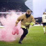 
              A member of staff removes a flare from the pitch during the English Premier League soccer match between Crystal Palace and Liverpool at Selhurst Park, London, Sunday, Jan. 23, 2022. (Adam Davy/PA via AP)
            