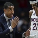 
              FILE - Connecticut head coach Kevin Ollie, left, talks with Connecticut's Terry Larrier and Christian Vital, right, during an NCAA college basketball game, Wednesday, Feb. 7, 2018, in Storrs, Conn. An independent arbiter has ruled that UConn improperly fired former men's basketball coach Kevin Ollie and must pay him more than $11 million, Ollie's lawyer said Thursday, Jan. 20, 2022. (AP Photo/Jessica Hill, File)
            