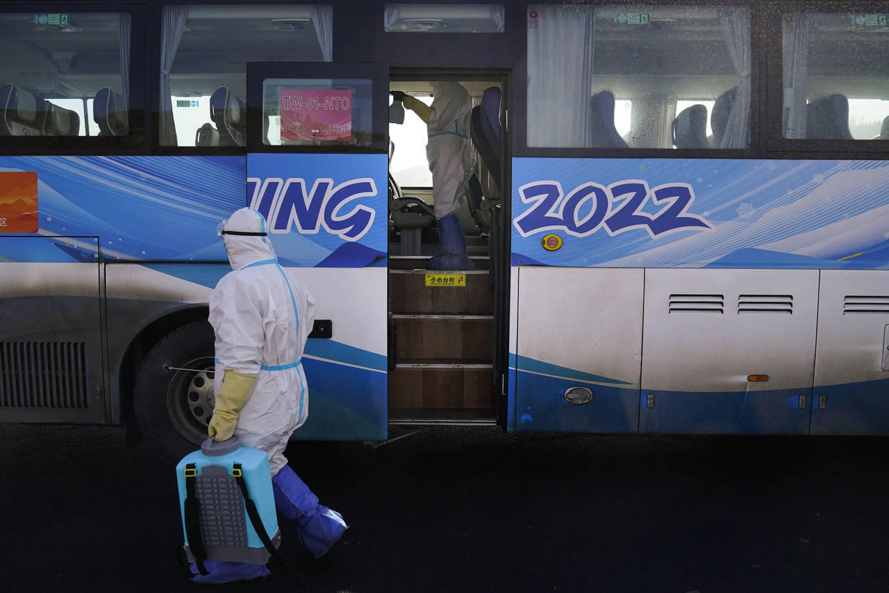 Workers in protective gear disinfect an Olympic shuttle bus ahead of the 2022 Winter Olympics, Sund...