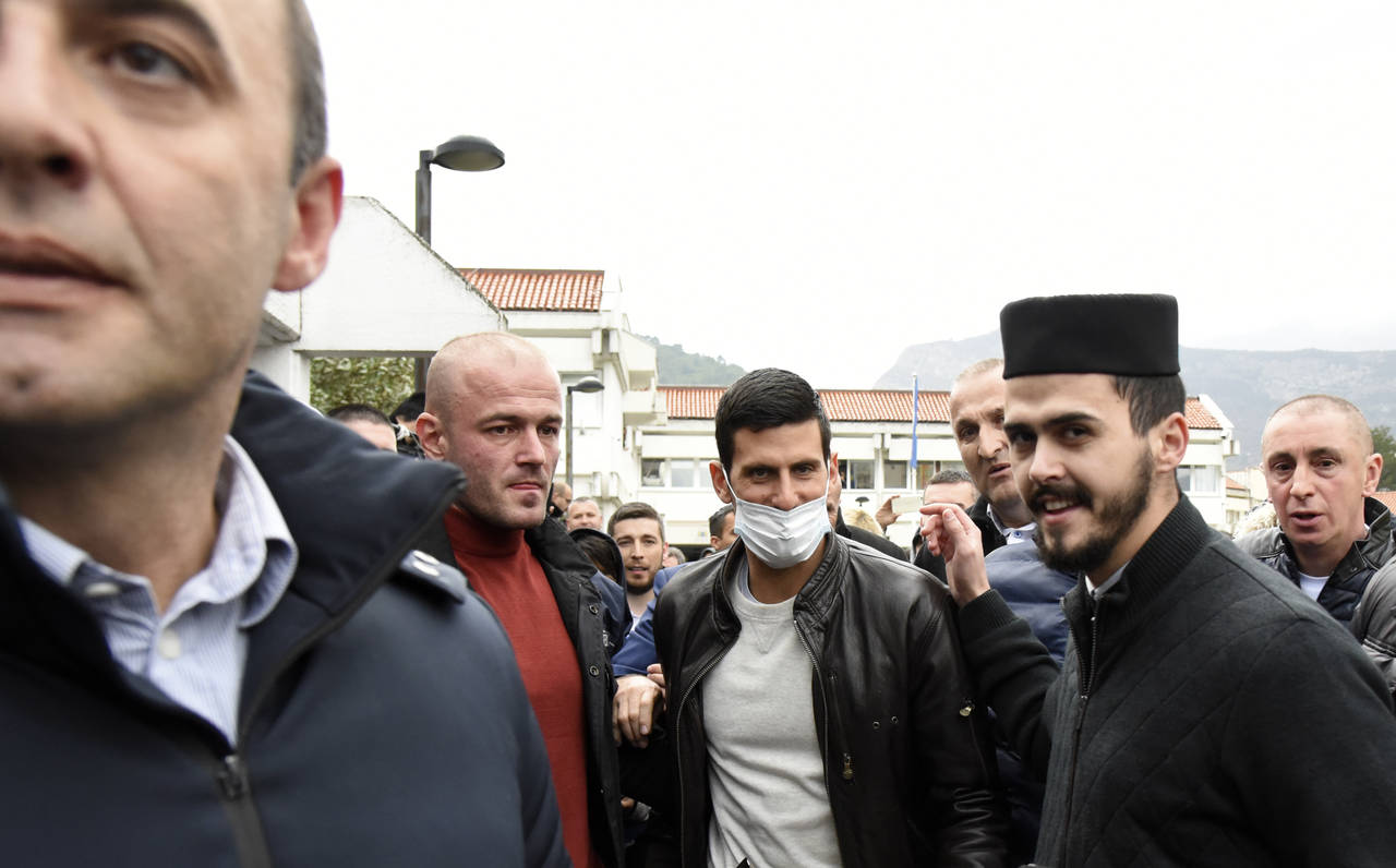 Serbian tennis player Novak Djokovic, center, wearing a face mask, arrives in the municipal buildin...