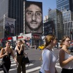 
              FILE - People walk by a Nike advertisement featuring Colin Kaepernick on display, Thursday, Sept. 6, 2018, in New York. While sports have always been indivisible from politics and public conflicts, there has been a major ground shift in the years since Michael Jordan made public neutrality on all non-sports issues an essential part of his brand. Now, there is almost an expectation of advocacy, especially with the precedent set by Colin Kaepernick's protests and the embrace by many of the Black Lives Matter cause. (AP Photo/Mark Lennihan, File)
            
