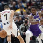 
              Denver Nuggets guard Facundo Campazzo, left, tries to retrieve the ball as Sacramento Kings guard Davion Mitchell defends during the first half of an NBA basketball game Friday, Jan. 7, 2022, in Denver. (AP Photo/David Zalubowski)
            