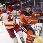 
              Calgary Flames' Christopher Tanev (8) checks Edmonton Oilers' Jesse Puljujarvi (13) during the second period of an NHL hockey game Saturday, Jan. 22, 2022, in Edmonton, Alberta. (Jason Franson/The Canadian Press via AP)
            