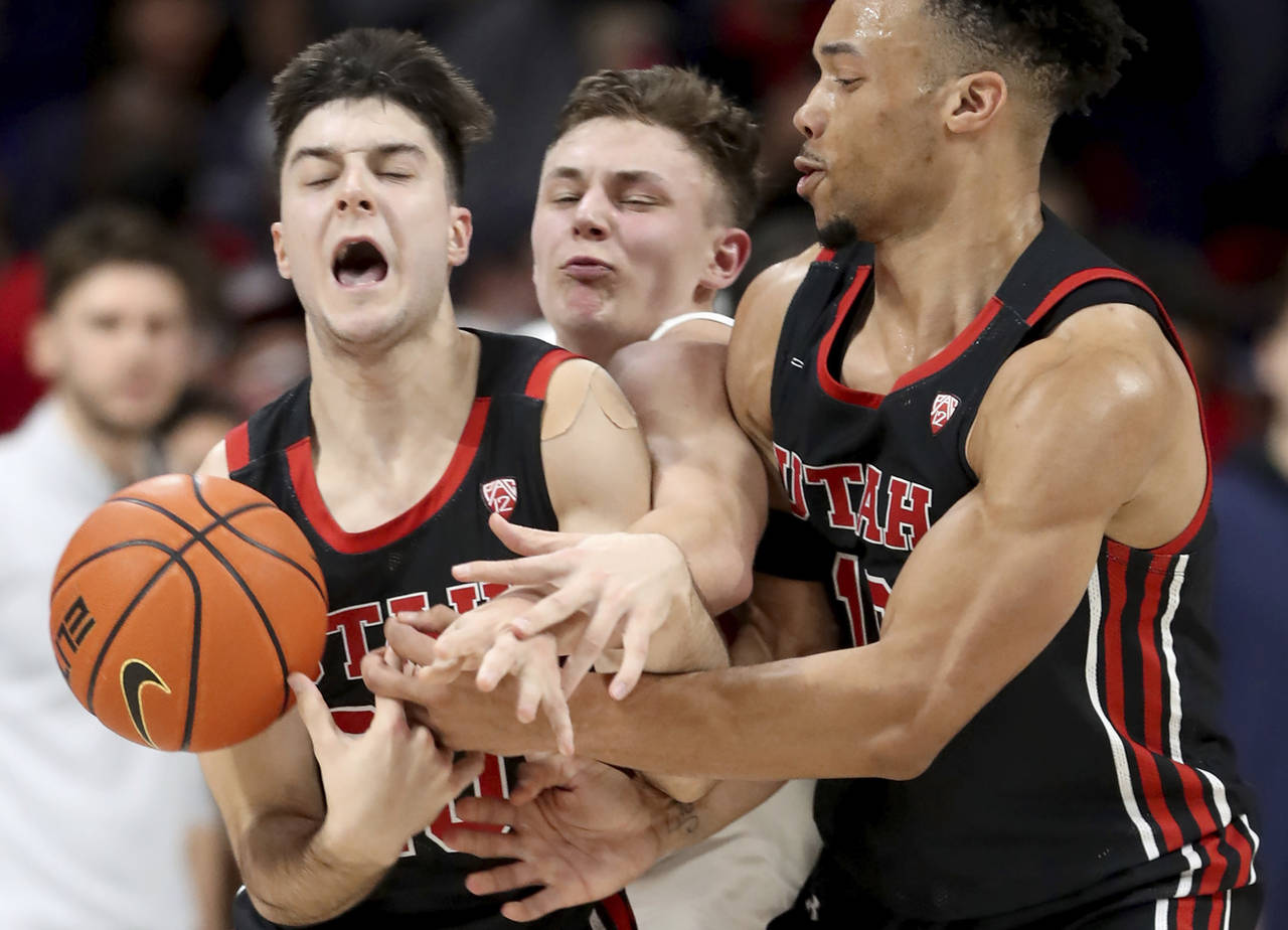 Arizona guard Pelle Larsson, center, is squeezed between Utah guards Lazar Stefanovic, left, and Ma...
