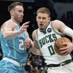 
              Milwaukee Bucks guard Donte DiVincenzo (0) drives to the basket while guarded by Charlotte Hornets forward Gordon Hayward (20) during the first half of an NBA basketball game in Charlotte, N.C., Monday, Jan. 10, 2022. (AP Photo/Jacob Kupferman)
            