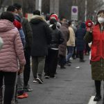 
              In this photo released by Xinhua News Agency, a volunteer wearing a face mask to protect from the coronavirus uses a loud speaker to give advise to masked residents as they line up for the coronavirus test during a mass testing in north China's Tianjin municipality, Sunday, Jan. 9, 2022. Tianjin, a major Chinese city near Beijing has placed its 14 million residents on partial lockdown after 41 children and adults tested positive for COVID-19, including at least two with the omicron variant. (Sun Fanyue/Xinhua via AP)
            