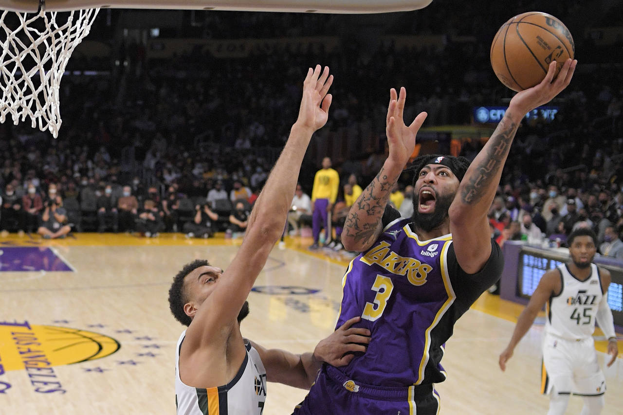 Los Angeles Lakers forward Anthony Davis, center, shoots as Utah Jazz center Rudy Gobert defends du...