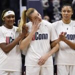 
              Connecticut's Dorka Juhász wipes her eye as the Hungarian national anthem is played as she stands with teammates Aaliyah Edwards and Olivia Nelson-Ododa before an NCAA college basketball game, Sunday, Feb. 27, 2022, in Storrs, Conn. (AP Photo/Jessica Hill)
            