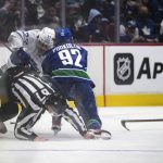 
              Toronto Maple Leafs' Timothy Liljegren (37), of Sweden, and Vancouver Canucks' Vasily Podkolzin (92), of Russia, collide with linesman Travis Gawryletz during the first period of an NHL hockey game in Vancouver, British Columbia, Saturday, Feb. 12, 2022. (Darryl Dyck/The Canadian Press via AP)
            