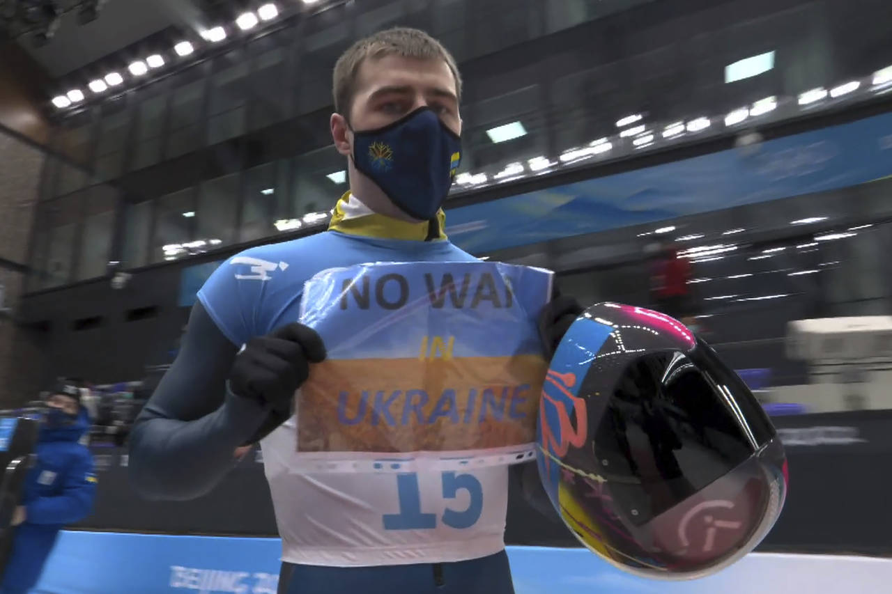 FILE - In this frame from video, Vladyslav Heraskevych, of Ukraine, holds a sign that reads "No War...