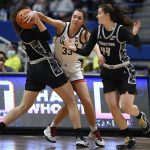 
              Connecticut's Caroline Ducharme, center, stops Georgetown's Graceann Bennett, left, from passing to Georgetown's Mary Clougherty, right, in the first half of an NCAA college basketball game, Sunday, Feb. 20, 2022, in Hartford, Conn. (AP Photo/Jessica Hill)
            