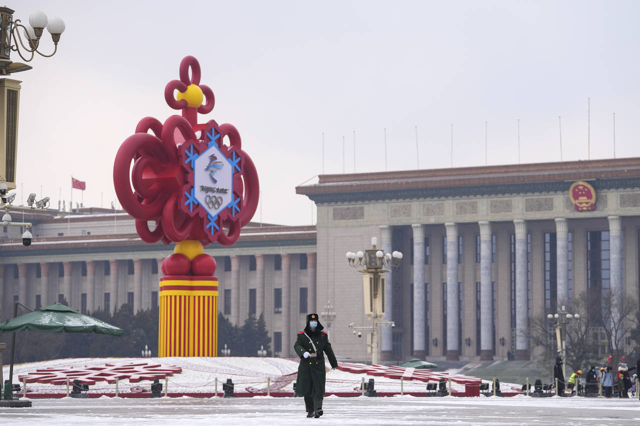 A paramilitary police officer wearing a face mask marches past a decoration for the Beijing Winter ...