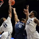 
              Connecticut guard Jalen Gaffney (0) shoots against Xavier's Dwon Odom (11) and Nate Johnson (10) during the first half of an NCAA college basketball game Friday, Feb. 11, 2022, in Cincinnati. (AP Photo/Jeff Dean)
            