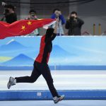 
              Gao Tingyu of China carries his country's flag after winning the gold medal and setting an Olympic record in the men's speedskating 500-meter race at the 2022 Winter Olympics, Saturday, Feb. 12, 2022, in Beijing. (AP Photo/Ashley Landis)
            