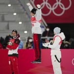 
              Ryoyu Kobayashi, of Japan, center, celebrates celebrates after winning gold as Manuel Fettner, of Austria, left, and Constantin Schmid, of Germany, watch during the flower ceremony for the men's normal hill individual ski jumping final at the 2022 Winter Olympics, Sunday, Feb. 6, 2022, in Zhangjiakou, China. (AP Photo/Matthias Schrader)
            