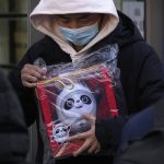 
              A man holds the Olympic mascot Bing Dwen Dwen doll which he purchased form a store selling 2022 Winter Olympics memorabilia in Beijing, Monday, Feb. 7, 2022. The race is on to snap up scarce 2022 Winter Olympics souvenirs. Dolls of mascot Bing Dwen Dwen, a panda in a winter coat, sold out after buyers waited in line overnight in freezing weather. (AP Photo/Andy Wong)
            