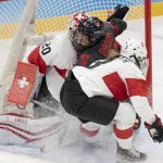
              Canada forward Melodie Daoust (15) runs into Switzerland goalkeeper Andrea Braendli (20) as Switzerland defender Sarah Forster (3) moves in during the first period of a women's hockey game Thursday, Feb. 3, 2022, at the Winter Olympics in Beijing. (Ryan Remiorz/The Canadian Press via AP)
            