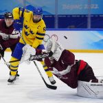 
              Latvia goalkeeper Ivars Punnenovs, bottom, dives for the puck as Sweden's Lucas Wallmark, not shown, scores a goal during a preliminary round men's hockey game at the 2022 Winter Olympics, Thursday, Feb. 10, 2022, in Beijing. In front of Punnenovs are Sweden's Anton Lander (58) and Latvia's Kristaps Roberts Zile (77). (AP Photo/Matt Slocum)
            
