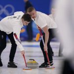 
              Britain's Grant Hardie, left, and Bobby Lammie sweep the ice during the men's curling final match between Britain and Sweden at the Beijing Winter Olympics Saturday, Feb. 19, 2022, in Beijing. (AP Photo/Brynn Anderson)
            