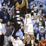 
              Louisville's Noah Locke, left, shoots a 3-point basket as North Carolina's Caleb Love, right, defends during the first half of an NCAA college basketball game in Chapel Hill, N.C., Monday, Feb. 21, 2022. (Ethan Hyman/The News & Observer via AP)
            