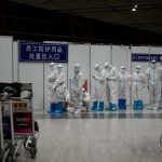 
              Olympic workers in protective clothing stand at the Beijing Capital International Airport after the 2022 Winter Olympics, Monday, Feb. 21, 2022, in Beijing. (AP Photo/Natacha Pisarenko)
            