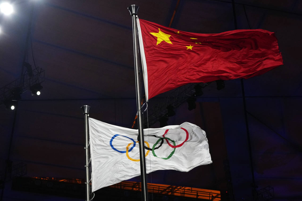 The Chinese and Olympic flags fly during the opening ceremony of the 2022 Winter Olympics, Friday, ...