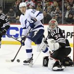 
              New Jersey Devils goaltender Jon Gillies (32) deflects the puck as Tampa Bay Lightning right wing Corey Perry (10) looks on during the second period of an NHL hockey game Tuesday, Feb. 15, 2022, in Newark, N.J. (AP Photo/Bill Kostroun)
            