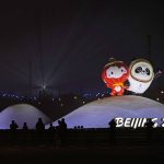 
              Residents past near the Paralympic mascot Shuey Rhon Rhon left, and Winter Olympic mascot Bing Dwen Dwen displayed near the National Stadium where a rehearsal for the opening ceremony of the 2022 Winter Olympics is taking place, in Beijing, China, Jan. 30, 2022. (AP Photo/Ng Han Guan)
            